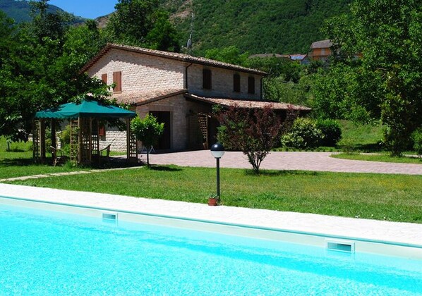 A swimming pool with a house in the background. - Vrbo Property (Cagli)