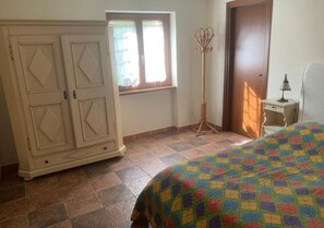 A bedroom with a bed, wardrobe, window, and a floor lamp. - Vrbo Property (Cagli)