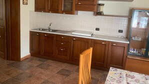 A kitchen with wooden cabinets, a sink, and a dining table with chairs. - Il Bosso Apartment in Cagli with a 15x6m saltwater pool (Cagli)