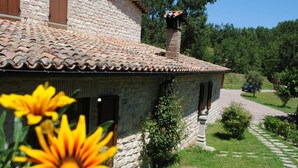 A stone house with a tiled roof, a chimney, and a paved driveway. - Il Bosso Apartment in Cagli with a 15x6m saltwater pool (Cagli)