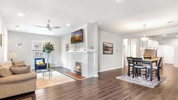 A spacious living room with a fireplace, a dining area with a table and chairs, and a kitchen in the background. - 3BR Home Downtown Atlanta | BeltLine | Mozley Park (Atlanta)