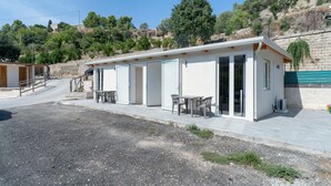 A modern, single-story building with a flat roof, large glass doors, and a patio area with outdoor seating.