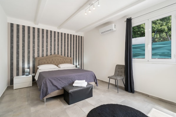 Une chambre moderne avec un lit, des tables de chevet, une chaise et une fenêtre donnant sur un beau paysage.