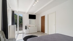 A modern bedroom with a bed, a desk, a chair, a television, and a wardrobe.