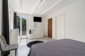 Une chambre à coucher moderne comprenant un lit, un bureau, une chaise, un téléviseur et une armoire.
