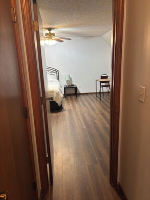 Ein Schlafzimmer mit Bett, Nachttisch, Schreibtisch und Deckenventilator.
