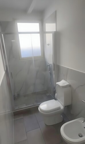 Un bagno con il water, bidet e cabina doccia.