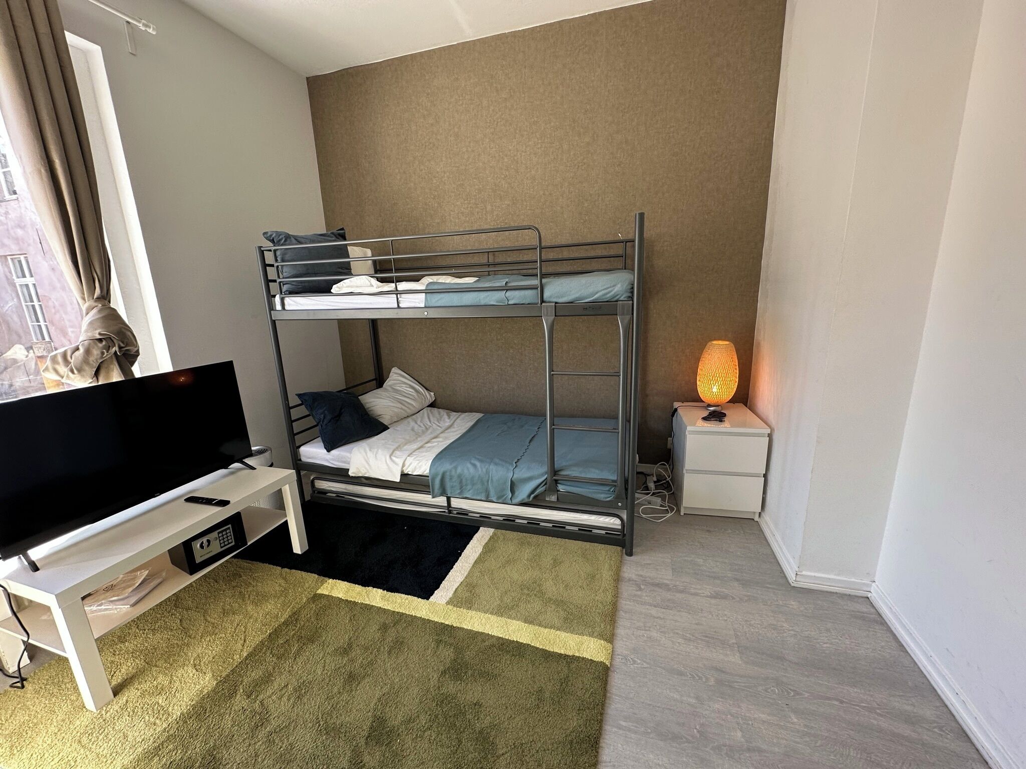 A bunk bed with a TV and a bedside table with a lamp.