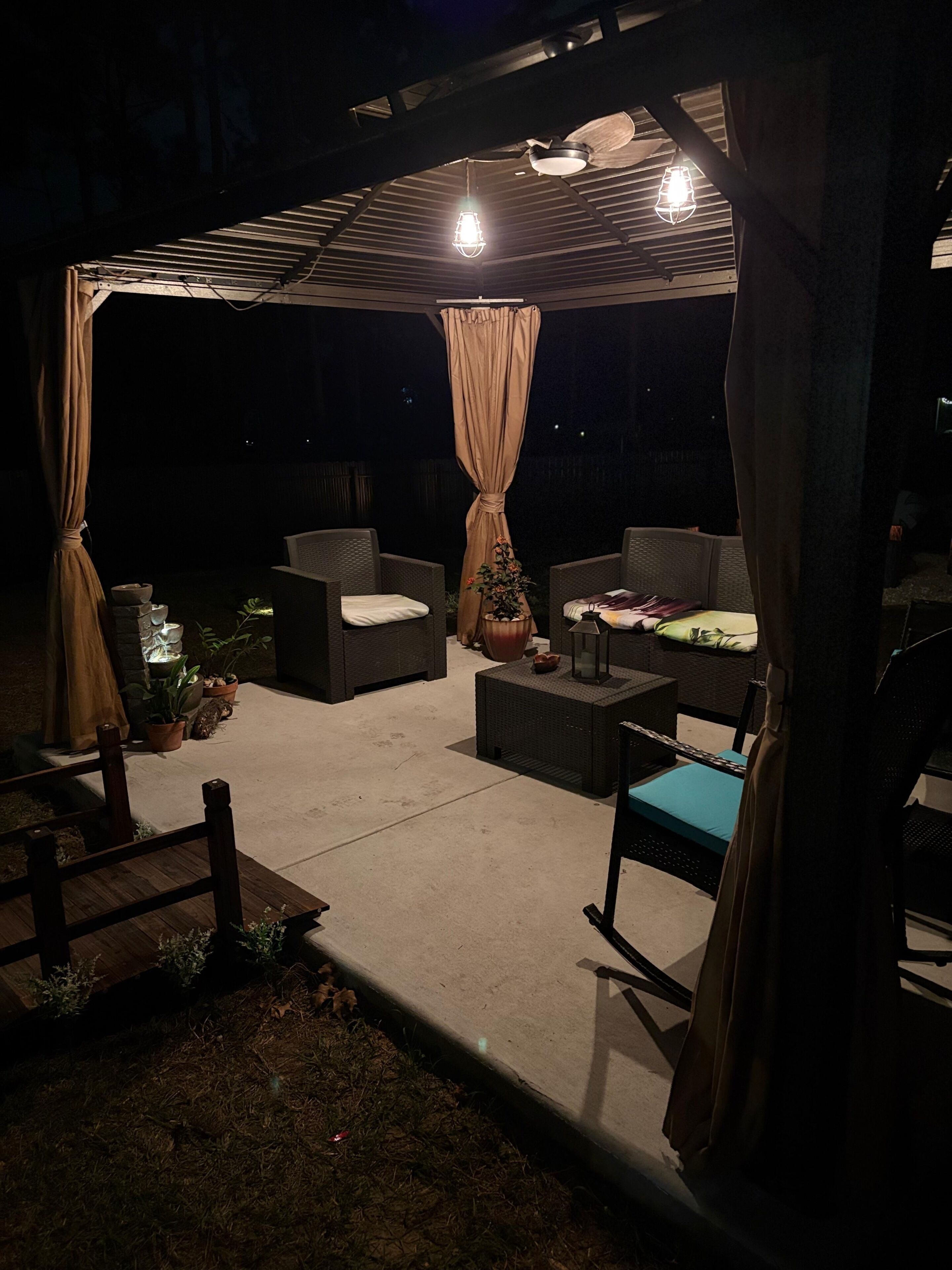 An outdoor patio with wicker furniture, a pergola, and a ceiling fan.