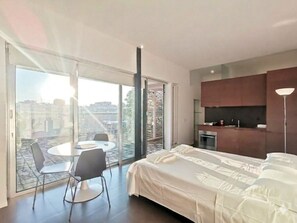 A modern bedroom with a large bed, a dining table with chairs, and a sliding glass door leading to a balcony. - Vrbo Property (Bari)