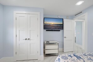 A bedroom with a bed, a TV mounted on the wall, a bedside table, and two doors.