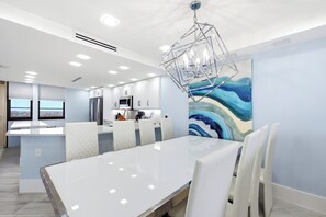 A modern kitchen with white cabinetry, stainless steel appliances, and a large island with seating.
