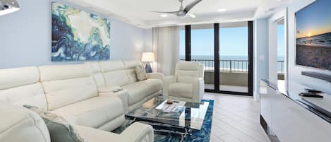 A modern living room with a sofa, armchairs, a coffee table, and a television.