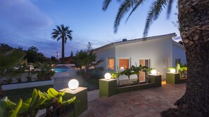 Ein modernes Haus mit Pool, umgeben von tropischer Vegetation und Palmen.