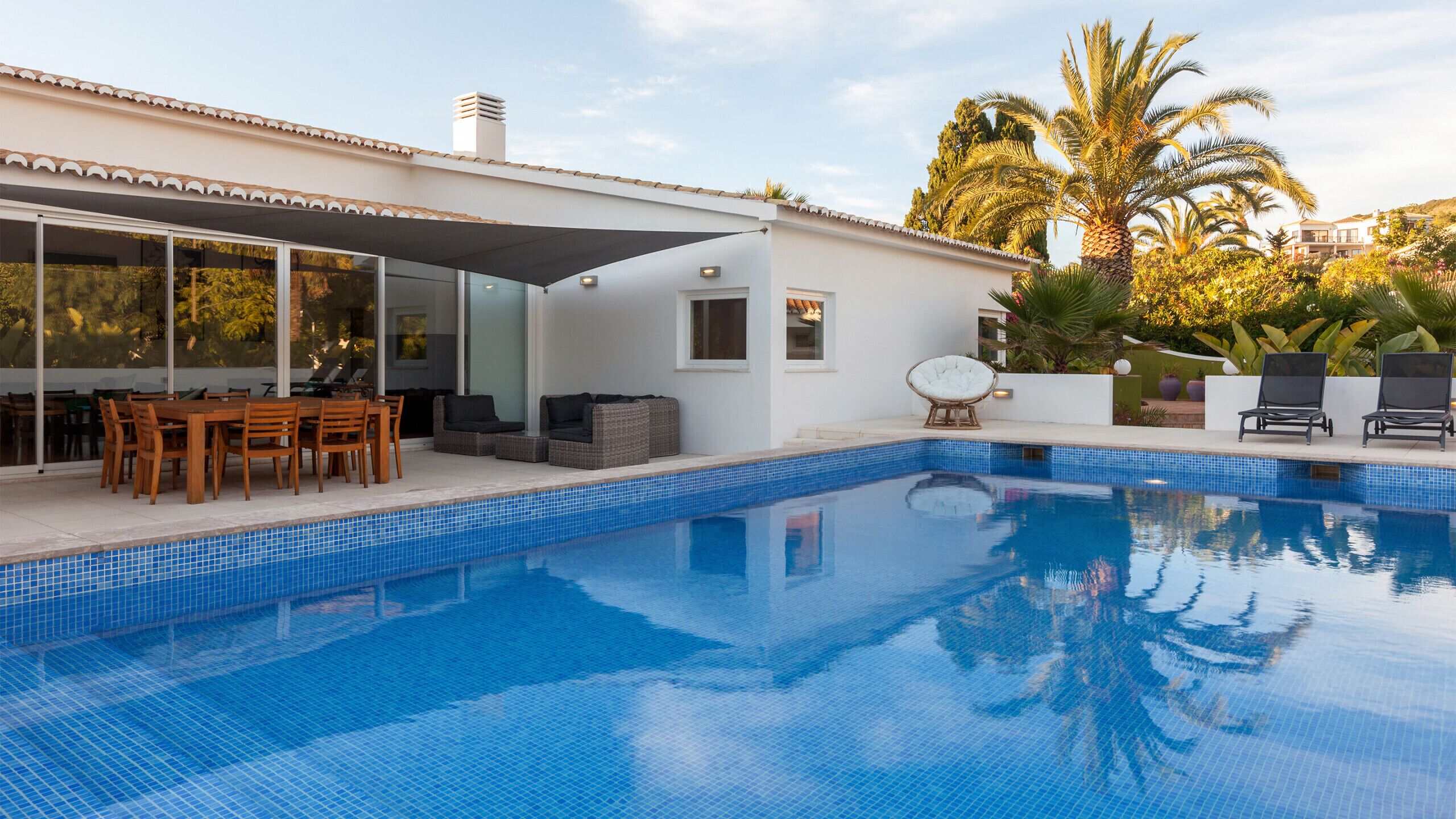 Une maison moderne dotée d’une piscine, de mobilier d’extérieur et d’un patio couvert.