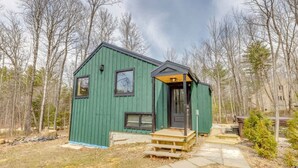 Une petite cabane en bois, peinte en vert, avec un porche à l’avant et une seule porte.