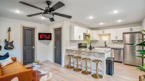A modern kitchen with white cabinets, a stainless steel refrigerator, and a bar stool area.