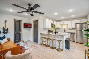 Una cocina moderna con armarios blancos, un refrigerador de acero inoxidable y una zona con taburetes de bar.