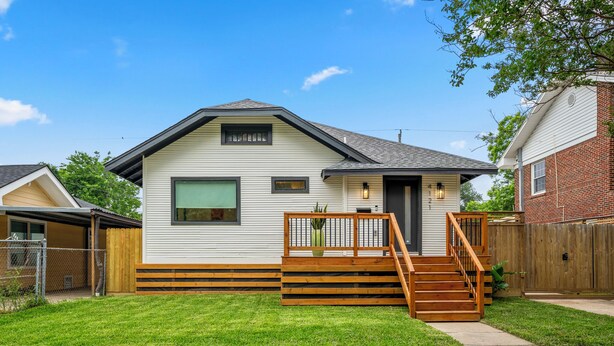 A single-story house with a front porch, a staircase leading to the front door, and a fenced backyard.