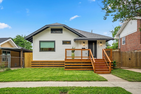 A single-story house with a front porch, a staircase leading to the front door, and a fenced backyard.