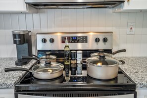 Een keuken met een inbouwfornuis, een koffiezetapparaat en een verzameling kruidenpotten.