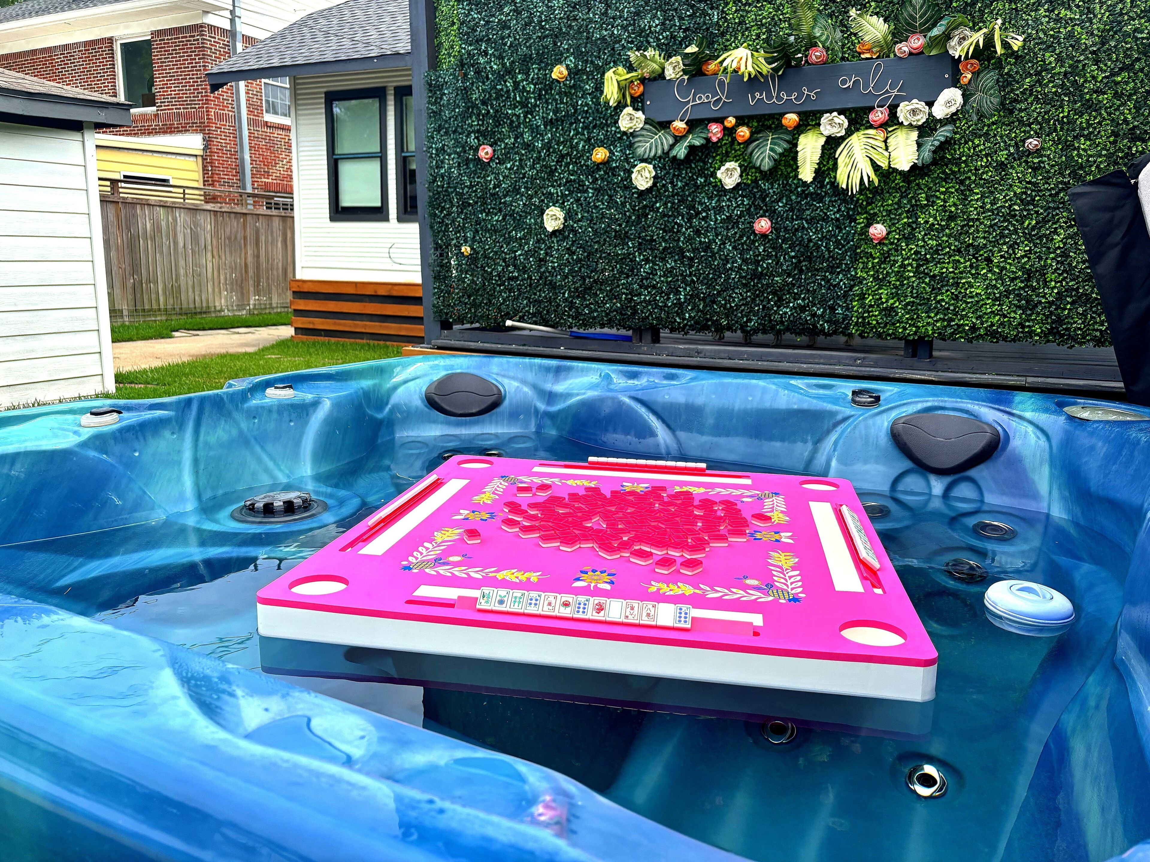 Un bain à remous avec un tapis rose, entouré d’un mur vert sur lequel est apposée une pancarte.