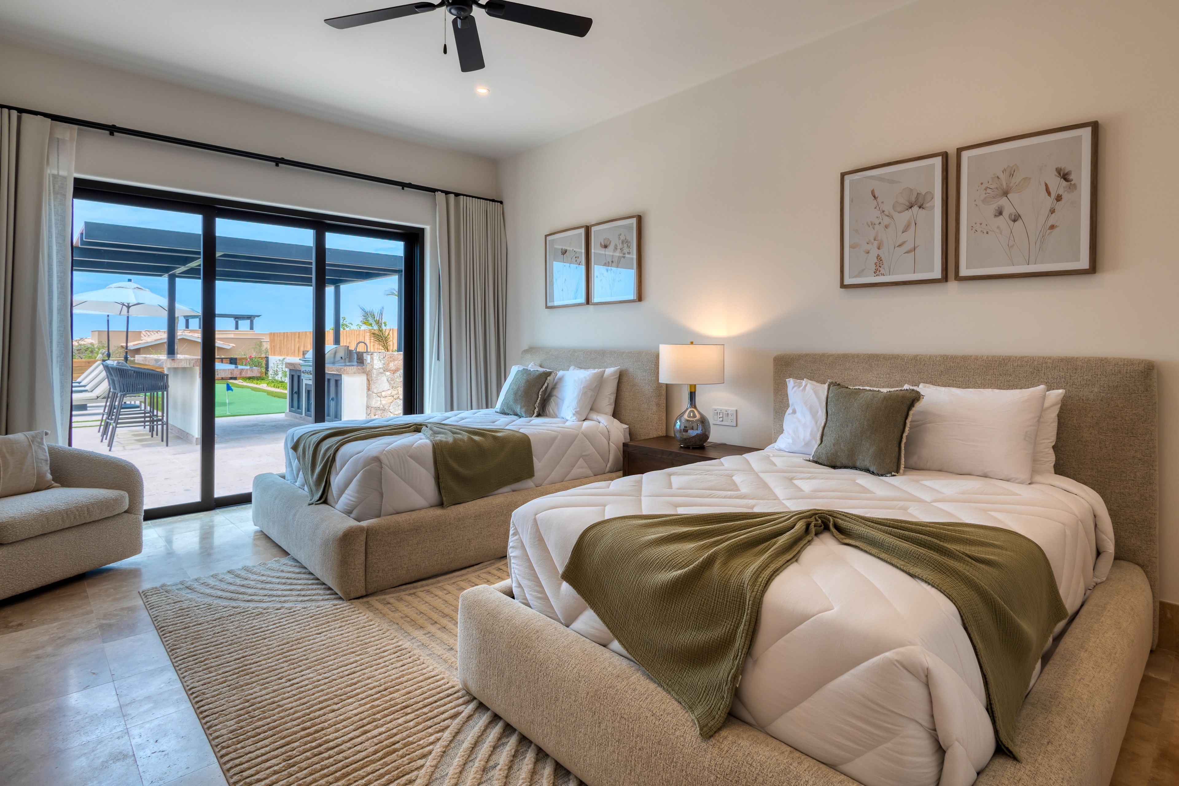 A modern hotel room with two beds, a sofa, a dining area, and a balcony with a view.