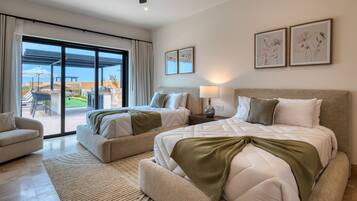 A modern hotel room with two beds, a sofa, a dining area, and a balcony with a view.
