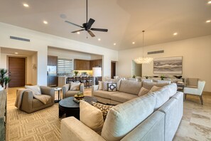 A spacious living room with a large sofa set, a coffee table, and a dining area in the background. - Luxury Coastal Retreat - Pool & World-class Golf (Cabo San Lucas)