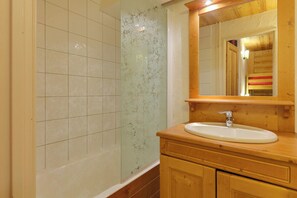 Un bany amb un penjador de fusta, un lavabo i un mirall.