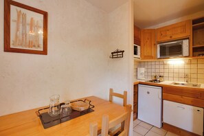 Ett kök med träskåp, en mikrovågsugn, en diskmaskin och ett matbord med stolar.