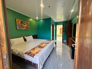 Quarto com cama, um quadro e porta que dá para um corredor.
