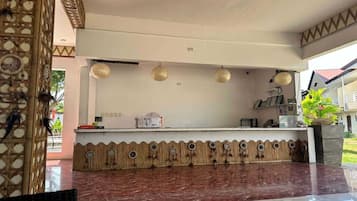 A reception area with a counter, decorative wall, and hanging lights.
