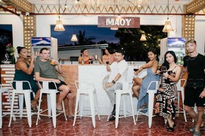 Un espace bar avec des tabourets blancs, une enseigne indiquant « MAOY », et une vue sur l’extérieur.