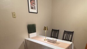 Spiseområde med bord, stole, bænk, lampe og et indrammet billede på væggen.