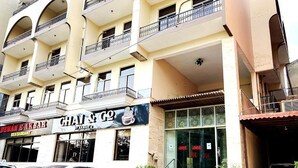 A multi-story building with balconies, a restaurant named 'GHAI & GO,' and parked cars. - Hotel Akbar International (Rawalpindi)