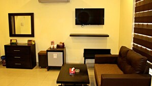 A living room with a TV, a small fridge, a coffee table, a sofa, and a cabinet. - Hotel Akbar International (Rawalpindi)