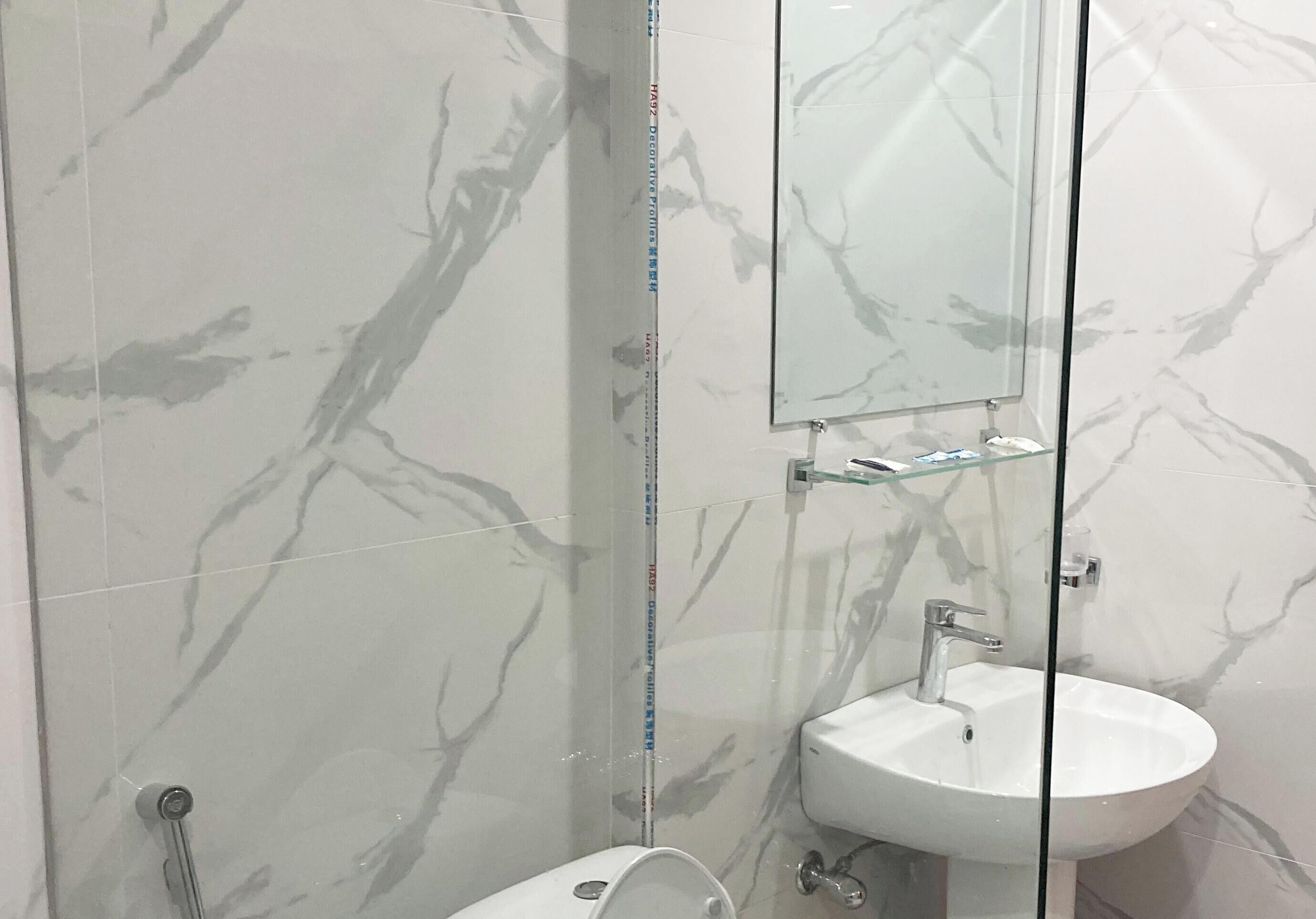 Un baño con cabina de ducha de vidrio, un lavabo blanco y un espejo sobre él.