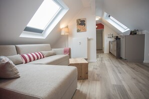 A modern loft apartment with a high ceiling, skylights, a kitchenette, and a cozy seating area. - Appartement - Winterbergerstrasse 3, nr. 511 | Neuastenberg (Winterberg)