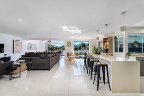 Ein modernes Wohnzimmer mit einer großen Couch, einem Essbereich mit Barhocker und einer Küche mit einer Bar.