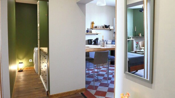 A hallway with a wooden floor, a table with a vase of flowers, and a mirror on the wall. - ATELIER CHARNOZ, heritage and Parodian ceramics (Paray-le-Monial)