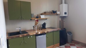 A kitchen with green cabinets, a wooden countertop, a dishwasher, a sink, a mixer, and a water heater. - ATELIER CHARNOZ, heritage and Parodian ceramics (Paray-le-Monial)