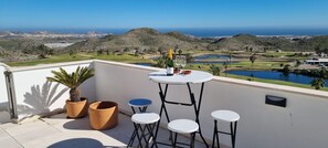 A balcony with a table, chairs, and potted plants. - Casa Aguilon Golf View (Pulpí)
