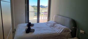 A bedroom with a bed, pillows, and a view of a balcony with outdoor furniture. - Casa Aguilon Golf View (Pulpí)
