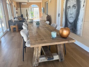 Ein Essbereich mit einem Holztisch, Stühlen, einer großen Vase und einem Wandgemälde.