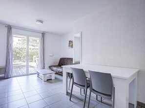 A modern room with a white desk, two chairs, a sofa, and a sliding glass door leading to an outdoor area.