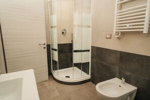 A bathroom with a glass-enclosed shower, a white sink, and a towel rack.