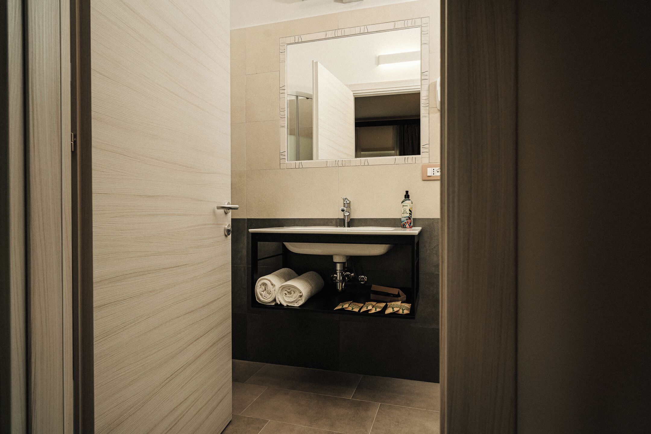 Een badkamer met een wastafel, spiegel en handdoekenkast.
