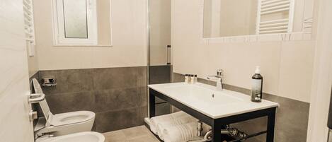 A bathroom with a toilet, bidet, sink, and towel rack.