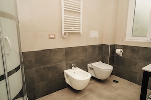 Un baño moderno con bidé, inodoro y cabina de ducha de vidrio.